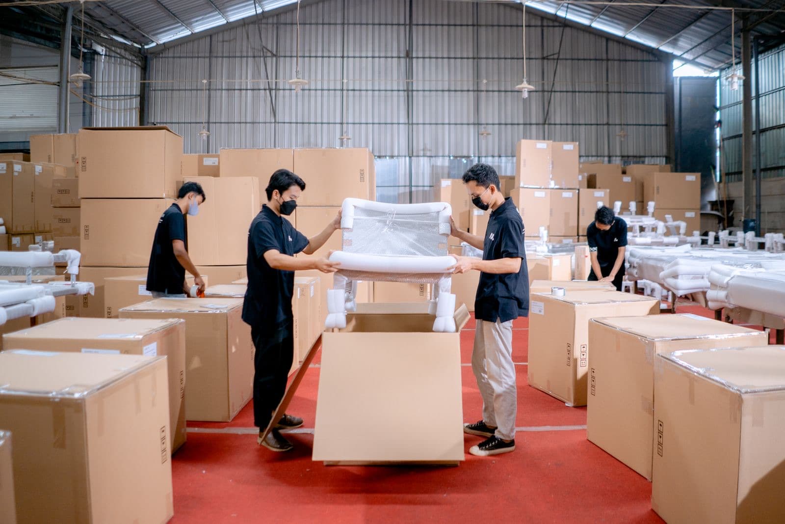 Warehouse staff packing an upholstered furniture piece for shipment